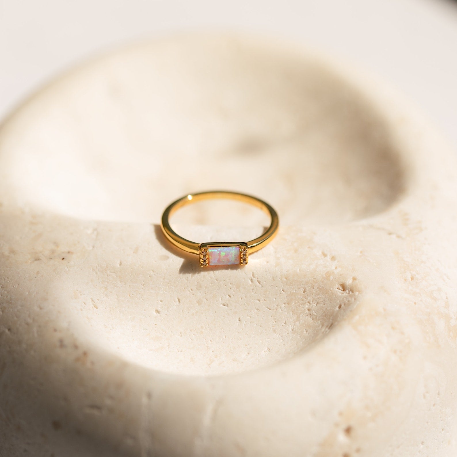 The Kiera Opal Baguette Ring features a rectangular opal stone set on a smooth band, making it an elegant choice for a promise ring or any special occasion.