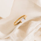 The Kiera Opal Baguette Ring showcases a rectangular opal stone, elegantly displayed on soft, cream-colored textured fabric.