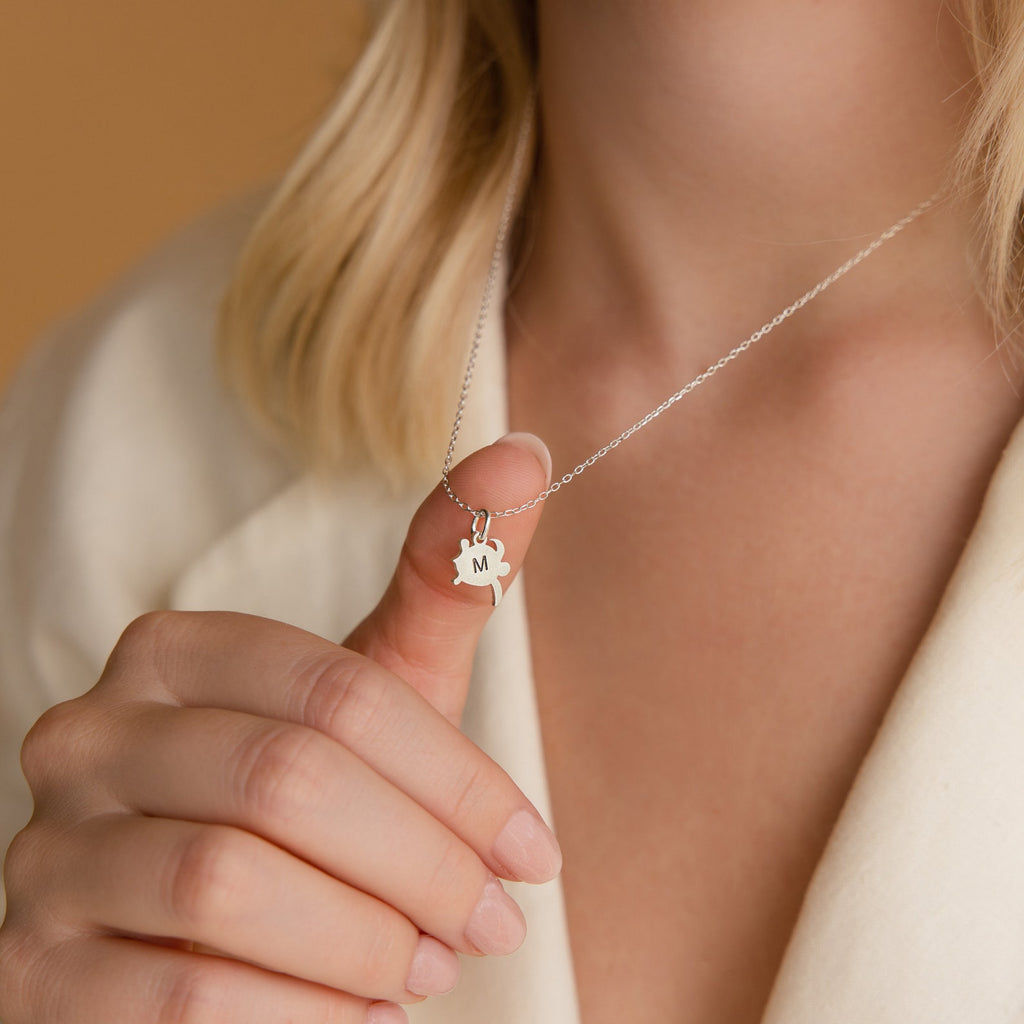A person holds the Pet Initial Necklace with an M pendant close to their chest—a thoughtful gift for any pet lover.