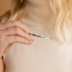 A woman holds a Custom Message Cuff—a silver engraved bracelet with the words I AM ENOUGH.
