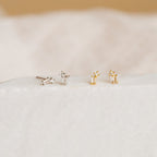 The Blair Baguette Diamond Drop Studs—two pairs in silver and gold—rest on a soft white surface, offering timeless style for minimalist earring lovers.