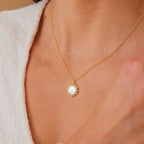 The Elia Sun Necklace—a gold sun-shaped pendant with a mother of pearl center—adds the perfect boho-luxe touch when paired with a white textured top.