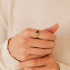 Close-up of a hand wearing the Ember Signet Ring, a gold chunky ring featuring a small black hexagonal stone on the middle finger—an ideal stylish men’s gift.