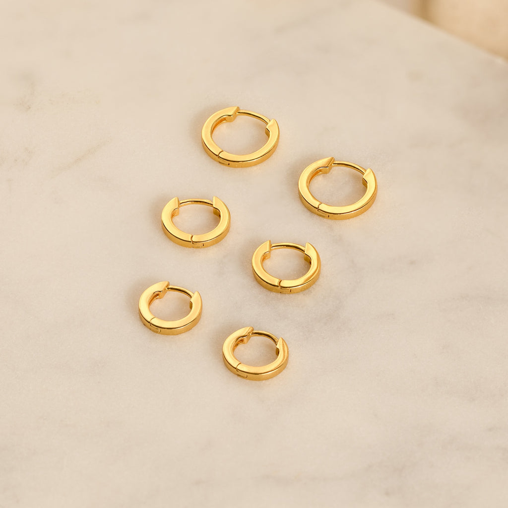 The Editor Huggie Earrings Set features six pairs of minimalist hoop earrings, beautifully arranged on a light marble surface—ideal for lovers of understated style.