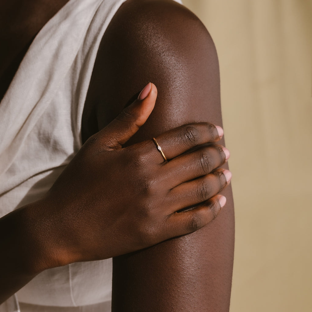 Wearing a Marquise Birthstone Ring, a person gently rests their hand on their upper arm while dressed in a sleeveless white top.