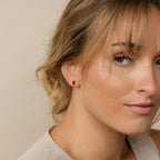 Close-up of a woman with light brown hair wearing Baguette Birthstone Studs and a beige top, looking at the camera—perfect inspiration for personalized gifts or unique jewelry.