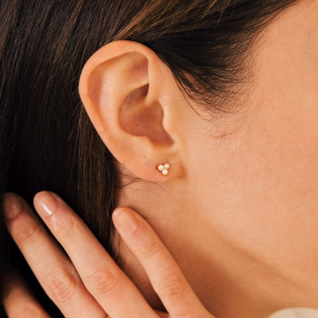 Close-up of a woman's ear adorned with Maud Pearl Studs, her hand gently touching her neck—a subtle nod to luxurious pearl jewelry and the elegance of a timeless gift.