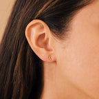 Close-up of a woman's ear wearing Trio Beaded Bar Studs—minimalist earrings with three beads, her hair tucked behind her ear; perfect for everyday wear.