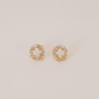 The Reina Cluster Studs are gold circular earrings featuring baguette-cut stones in a wreath-like pattern, making them the perfect elegant bridal accessory for your special day.