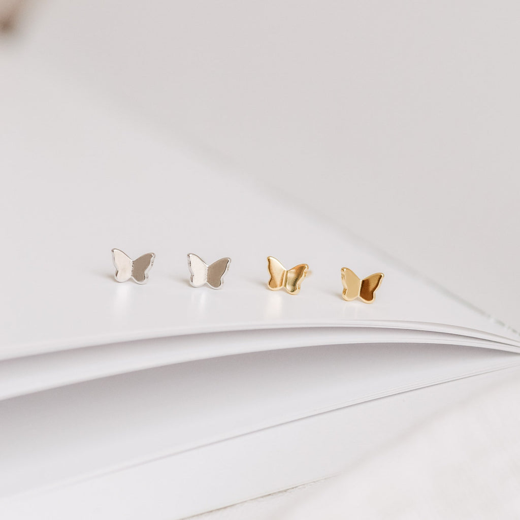 A group of butterflies on a white book, reminiscent of the delicate Emilia Butterfly Studs.
