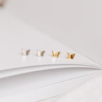 A group of butterflies on a white book, reminiscent of the delicate Emilia Butterfly Studs.