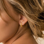 A close-up of a woman's ear adorned with Ribbed Link Hoops.