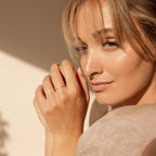 A woman with blonde hair and natural makeup poses in sunlight, highlighting the Jessie Duo Pave Ring on her finger.