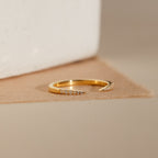 The Jessie Duo Pave Ring is a gold open ring with a subtle design, featuring small clear stones on each tapered end, displayed against a neutral background.