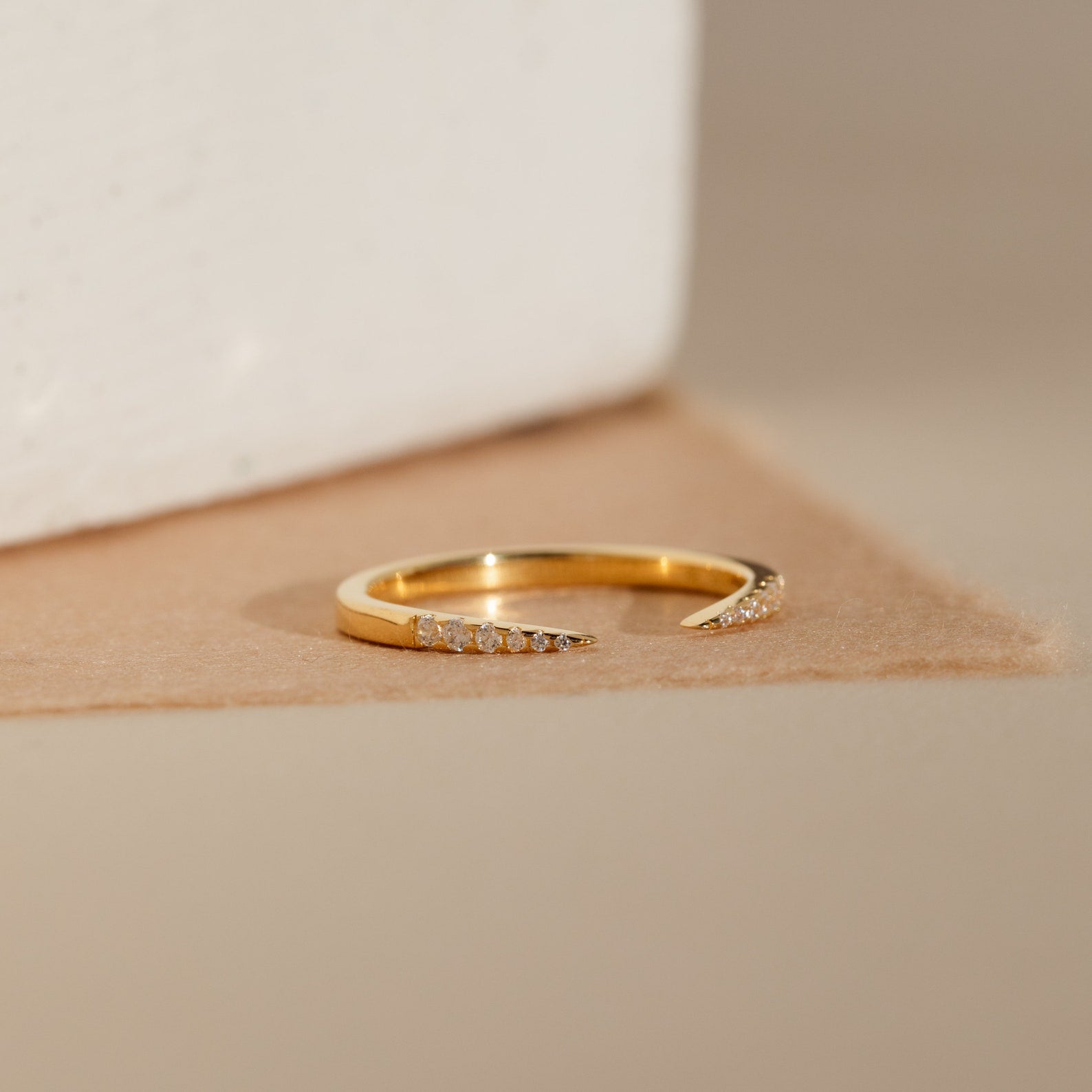 The Jessie Duo Pave Ring is a gold open ring with a subtle design, featuring small clear stones on each tapered end, displayed against a neutral background.