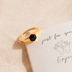 The Ember Signet Ring—a chunky black ring with a hexagon stone—rests on a handwritten note with drawn hands, making it the perfect men's gift.
