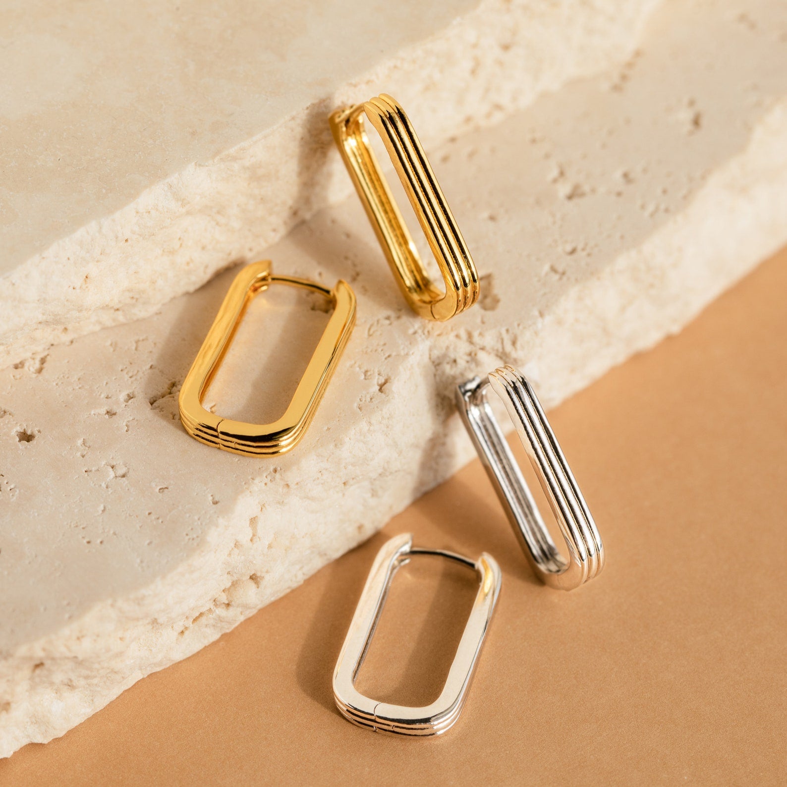 Two gold and two silver Large Ribbed Link Hoops displayed on textured stone, perfect for minimalist jewelry lovers.