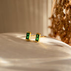 Baguette Birthstone Studs featuring rectangular green stones are shown on a white surface in soft, natural light—ideal as personalized gifts for any occasion.