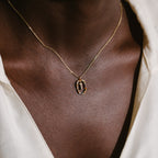 The Rainbow Initial Necklace features a letter T pendant, elegantly worn above a white shirt collar—a stylish, personalized accessory for everyday wear.