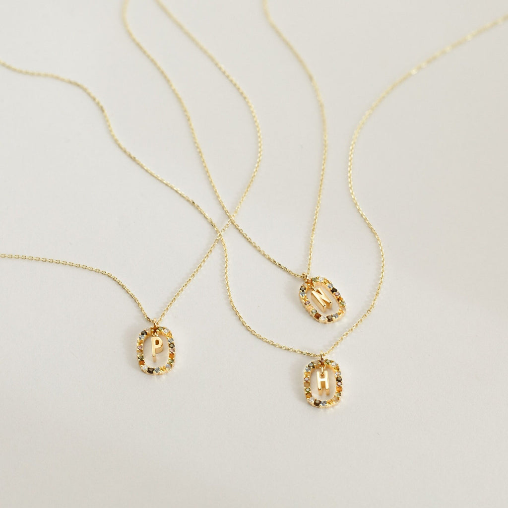 A selection of gold necklaces with letters, including a personalized initial necklace and the colorful Rainbow Initial Necklace.