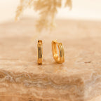 Two Ribbed Link Hoops with a ribbed rectangle design rest on a beige marble surface, their geometric style complemented by the soft, neutral background.