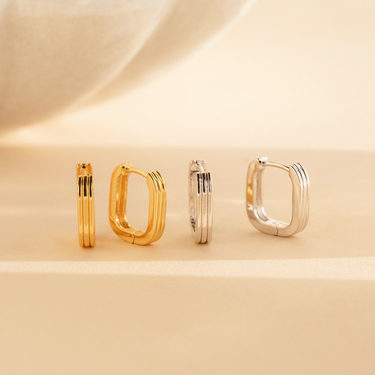 A set of gold and silver earrings, featuring stylish Ribbed Link Hoops and trendy huggie hoops.