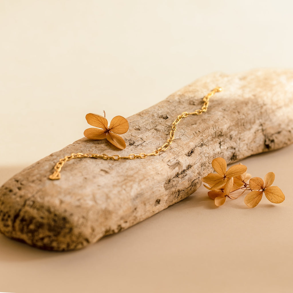 The Roxy Paperclip Chain Bracelet features a bold, chunky design and rests on driftwood with dried flowers, set against a soft beige background.