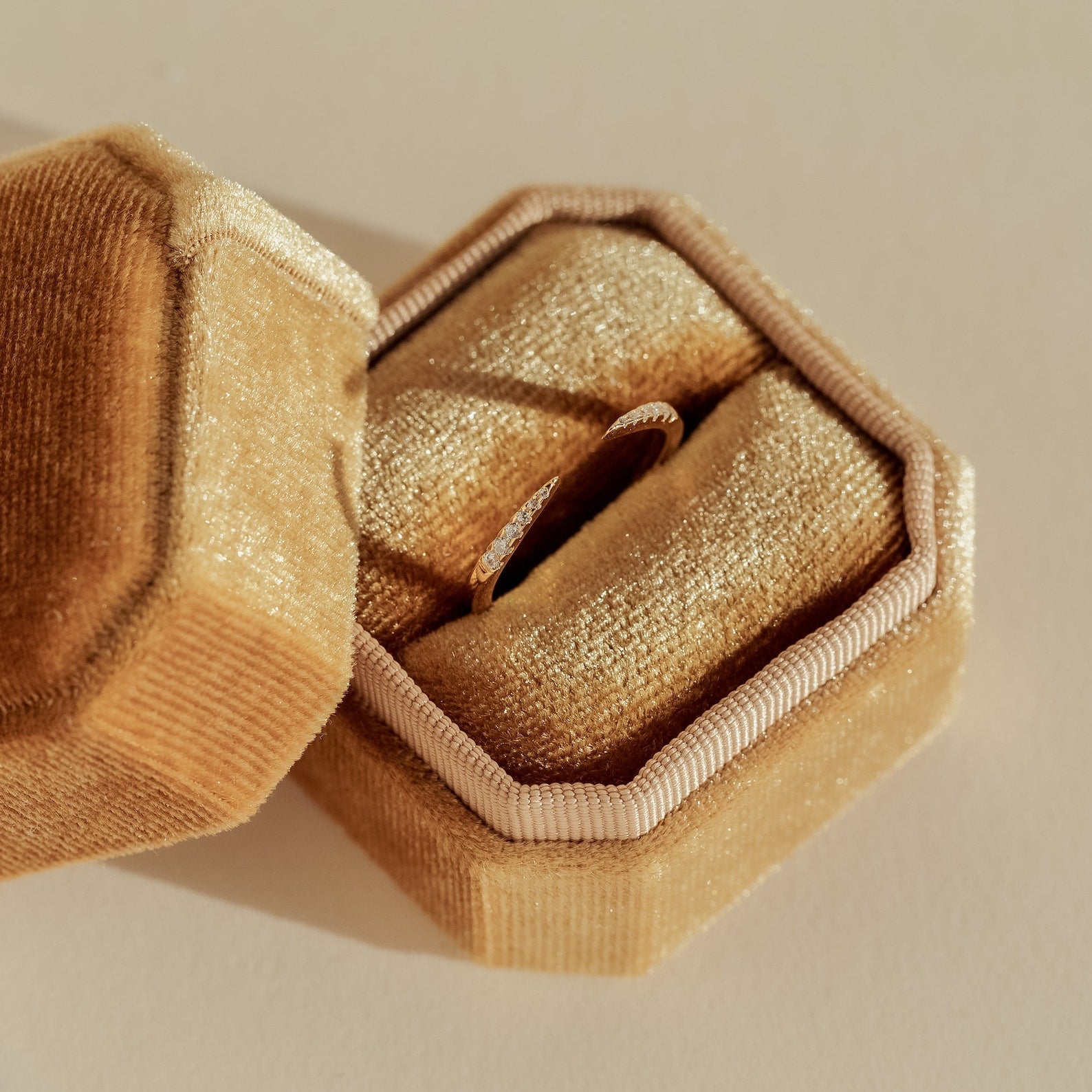 The Jessie Duo Pave Ring, a thin and dainty band, is shown inside a gold velvet ring box on a light-colored surface.