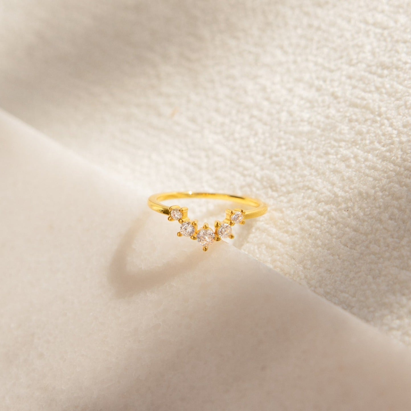 The Marina Chevron Ring features small, sparkling stones set in a delicate chevron pattern, offering everyday elegance as a dainty gold band.