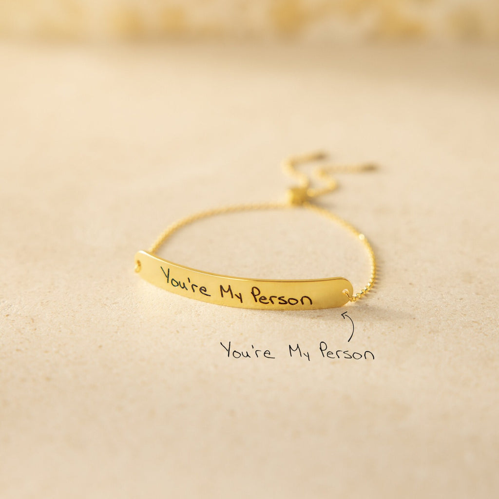 The Slider Handwriting Bracelet rests on a beige surface, engraved with "You're My Person." This personalized bracelet also includes your custom handwritten message below for a heartfelt touch.