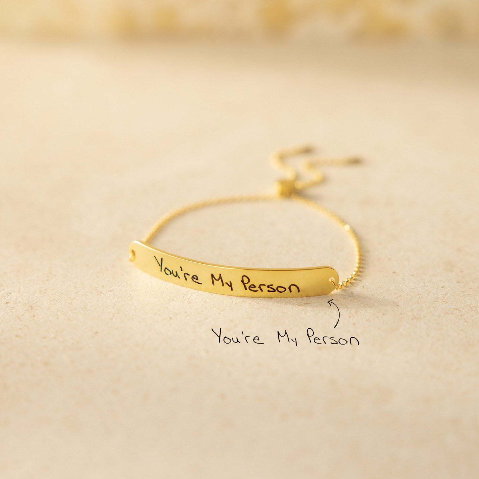 The Slider Handwriting Bracelet rests on a beige surface, engraved with "You're My Person." This personalized bracelet also includes your custom handwritten message below for a heartfelt touch.