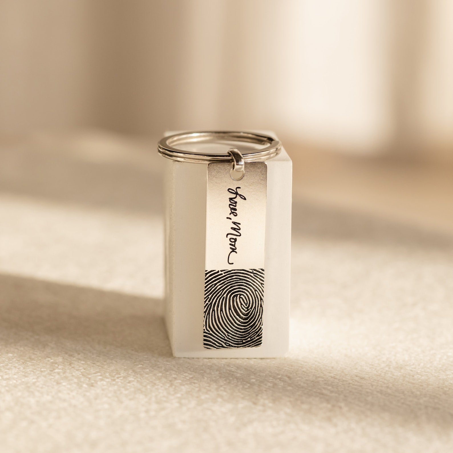 The Fingerprint Bar Keychain features a unique fingerprint and "Love Mom" engraving on a small silver rectangular bar—a perfect personalized keepsake.