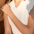 A woman in a sleeveless white knit sweater wears the Interlocking Circles Bracelet—a delicate, minimalist piece that's an elegant choice for an anniversary gift.