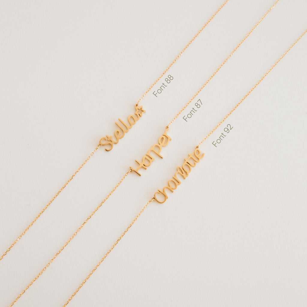 Three gold Maine Kid's Name Necklaces with personalized name pendants—Stella, Harper, and Charlotte—in various fonts. A charming custom piece for a unique touch.