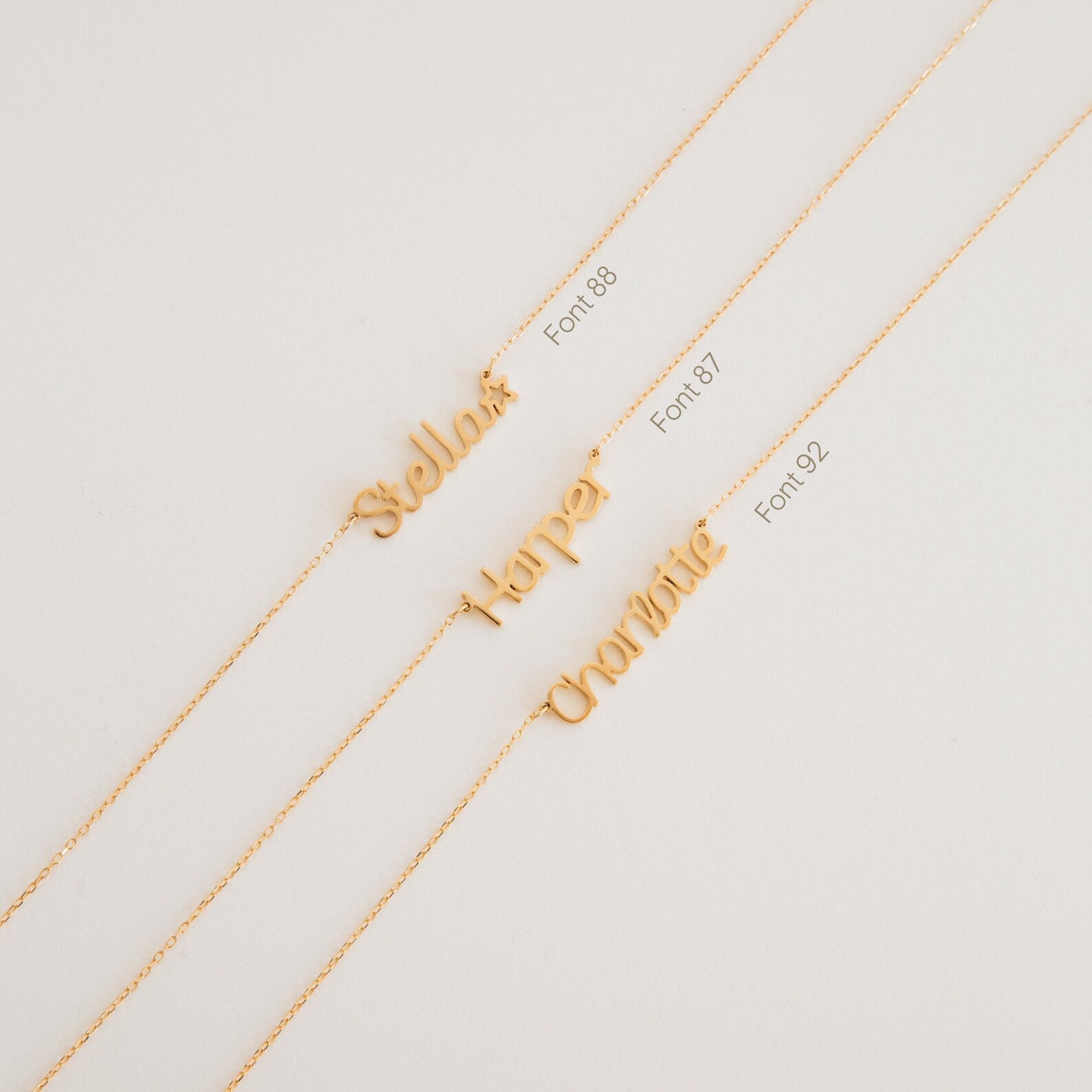 Three gold Maine Kid's Name Necklaces with personalized name pendants—Stella, Harper, and Charlotte—in various fonts. A charming custom piece for a unique touch.