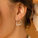 Close-up of a woman’s ear wearing London Heart Name Earrings, featuring a heart-shaped silver hoop with a custom name inside—ideal as personalized gift jewelry.