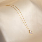 Vintage Rose Necklace: Gold chain with an oval pendant showcasing a delicate white floral design on a soft beige background—an elegant Mother’s Day gift.