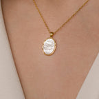 The Vintage Rose Necklace features a gold chain with an oval white pendant and raised floral design, making it a charming Mother's Day gift.