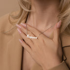 A woman with manicured nails touches a Natural Name Necklace in Box Chain featuring "Benjamin" in elegant cursive—a thoughtful gift for any occasion.