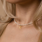 Close-up of a woman wearing the Newsletter Pearl Initial Necklace in Rose Gold—a minimalist piece with customizable initial charm and elegant pearls.