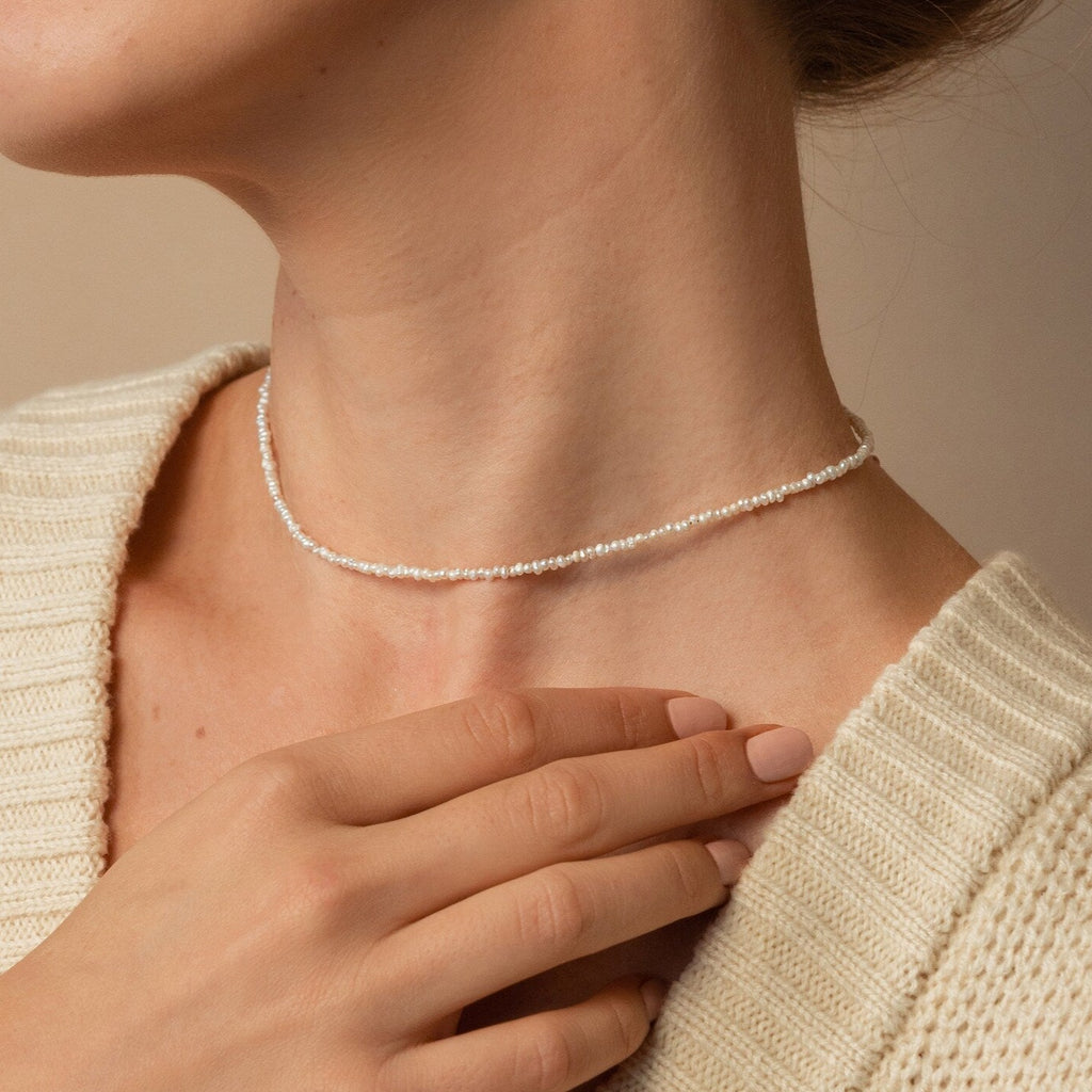 Dainty off white freshwater pearl necklace with petite, irregularly shaped pearls, styled on neck to display choker fit and delicate fine pearls. 