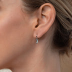 Close-up of a woman's ear wearing Opal Moon Mini Hoops, small silver crescent earrings perfect for adding to your earring stack.