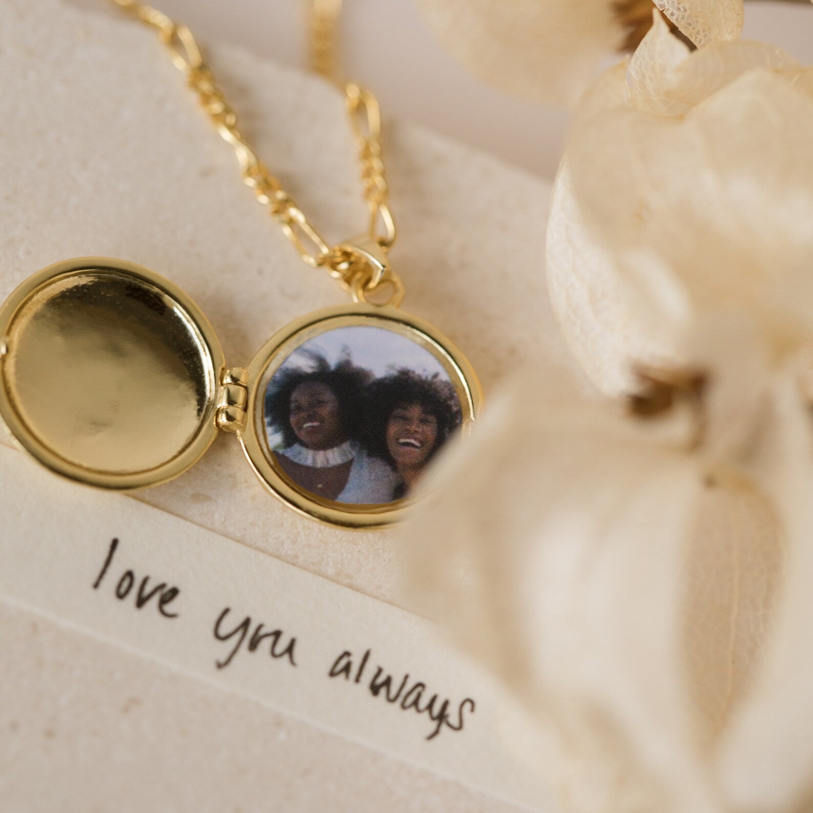 The Earth Locket Necklace features a gold finish and holds a photo of two smiling women beside a “love you always” note—a meaningful travel keepsake to cherish.