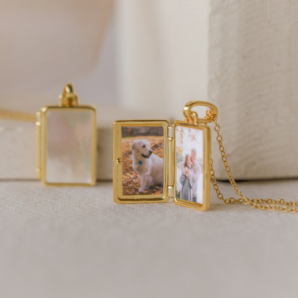 The Endless Love Locket Necklace opens to reveal cherished images of a dog and two children inside, elegantly displayed on a light surface—a timeless keepsake jewelry piece.