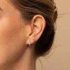Close-up of a woman's ear wearing the Amaya Marquise Threaders, dainty diamond cluster earrings, and delicate silver studs with stones. Hair is tied back for an elegant jewelry look.