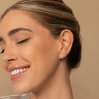 Woman with closed eyes and a smile wears the elegant Amaya Marquise Threaders against a beige background—delicate diamond cluster earrings that exude effortless charm.