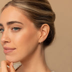 A woman with light eyes and smooth skin wears the elegant Amaya Marquise Threaders, looking thoughtful against a beige background.