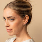 Blonde-haired woman with an updo, wearing a white top and elegant Heart Knot Studs, looking to the left.