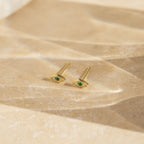 Haven Emerald Eye Studs showcased on a textured beige surface in soft lighting.