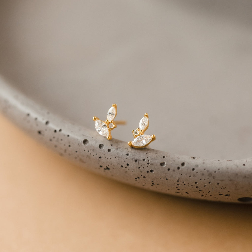 Flora Marquise Studs—gold stud earrings featuring three marquise-shaped crystals, shown on a speckled ceramic dish. Perfect minimalist earrings for everyday elegance.
